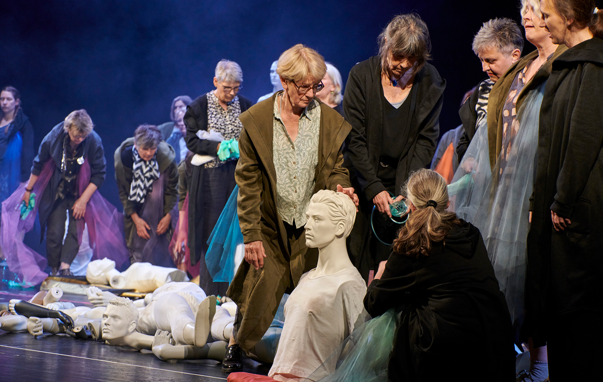 Mehrere Personen stehen um wei&szlig;e, kopflose Puppen herum und betrachten sie.